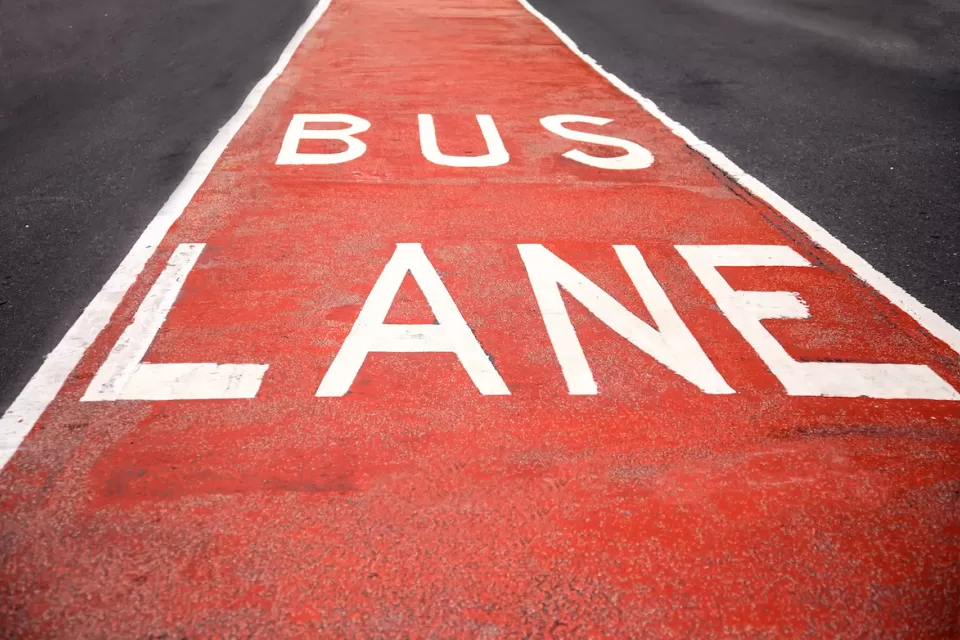 Close-up of red and white BUS LANE sign painted in street lane.